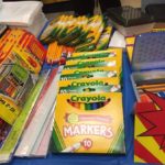 Crayola Markers, Crayons, Rulers, Pencils & glue sticks are displayed on table ready to be distributed to children at the 2018 Back to School Block Party.