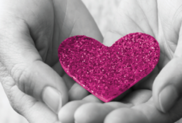 black and white hands holding a pink sparkly heart