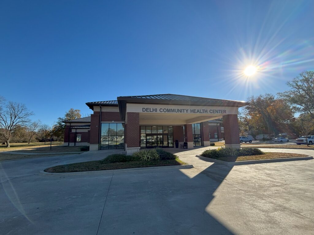 front of the Delhi Community Health Center building with the sun shining behind it